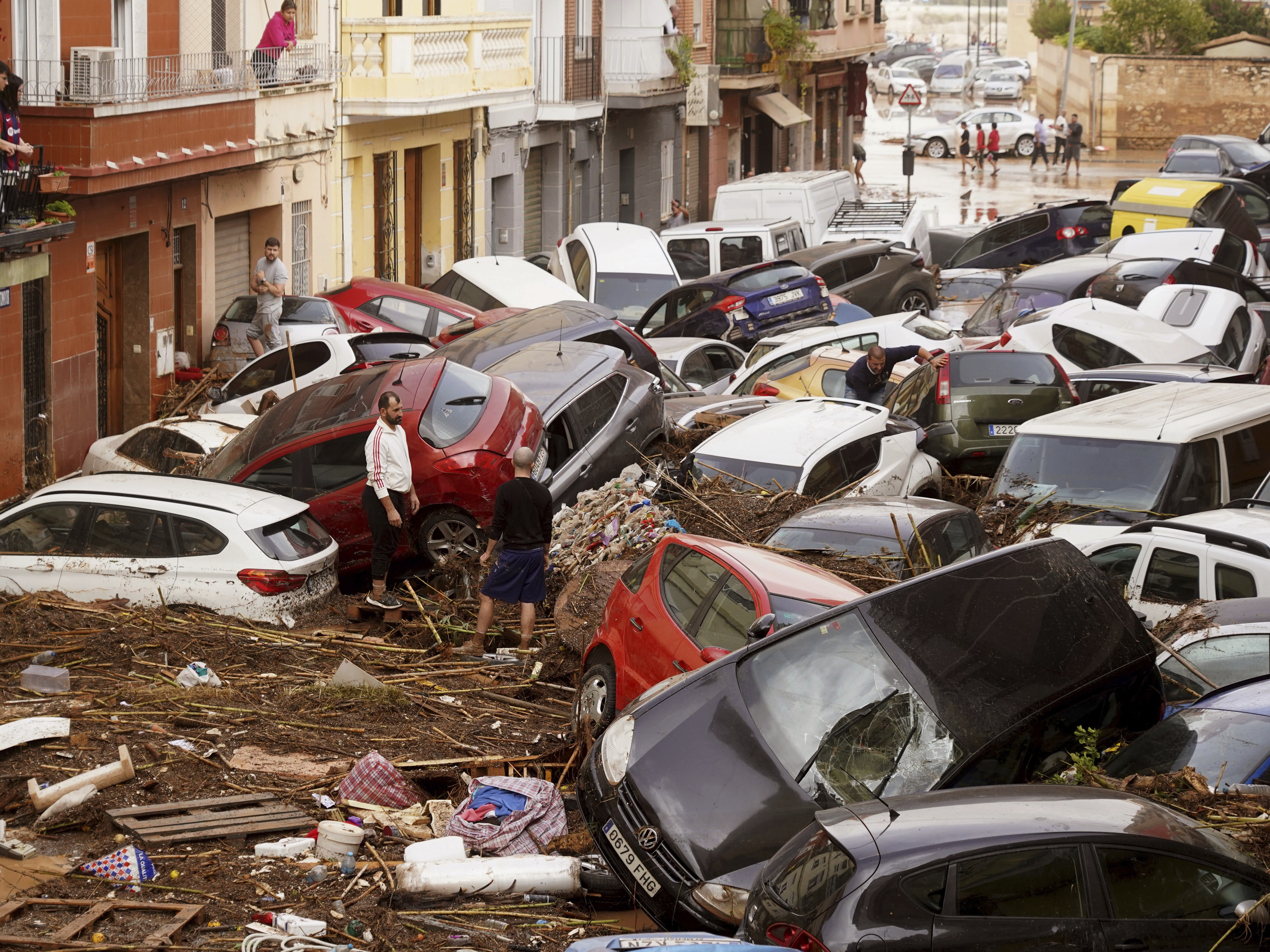caption: Residents look at cars piled up after being swept away by floods in Valencia, Spain, Wednesday.