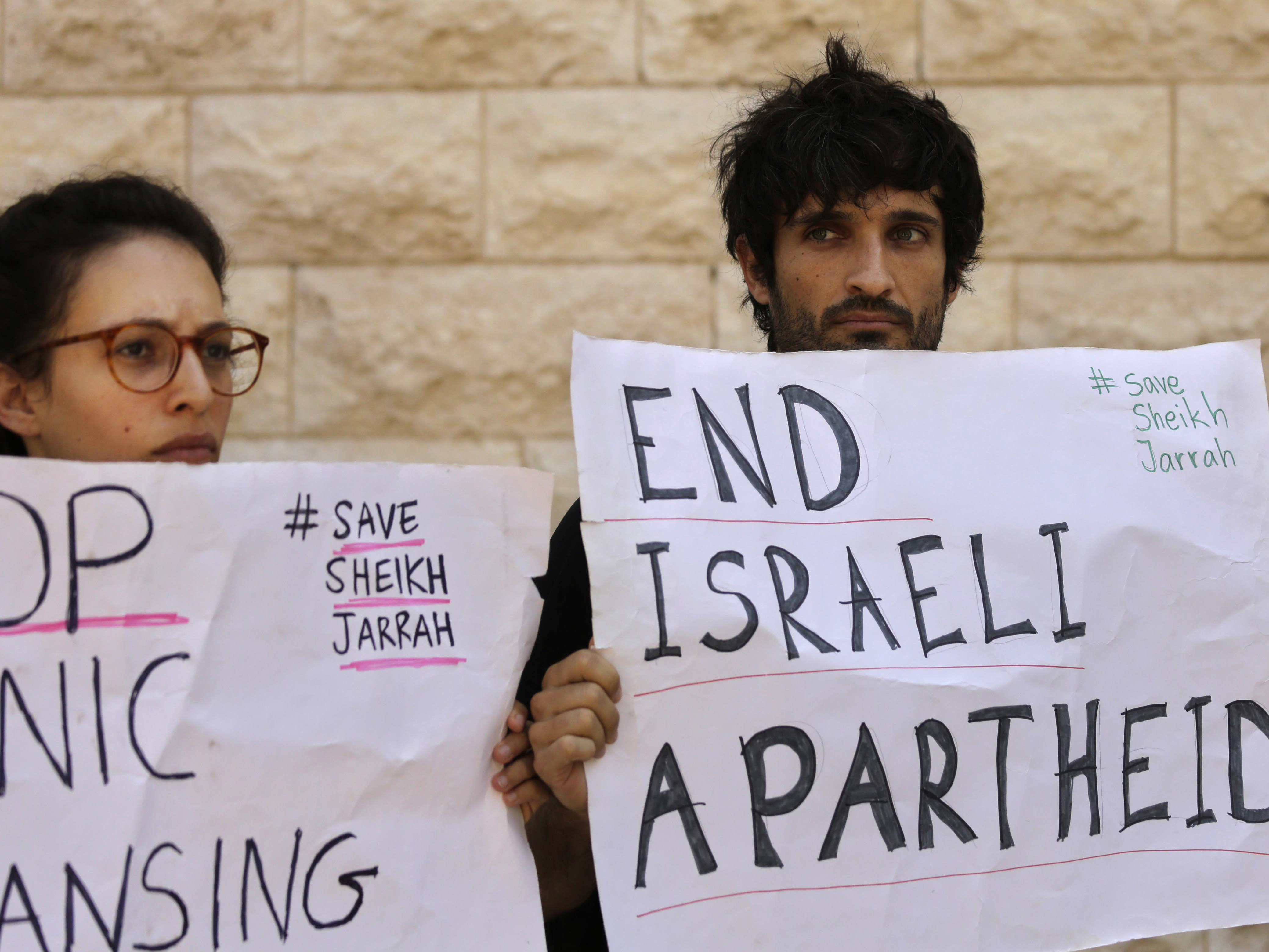 caption: Protesters hold signs during a hearing on the possible evictions of Palestinians from the Sheikh Jarrah neighborhood of Jerusalem, outside the Israeli Supreme Court in Jerusalem on Monday, Aug. 2, 2021.