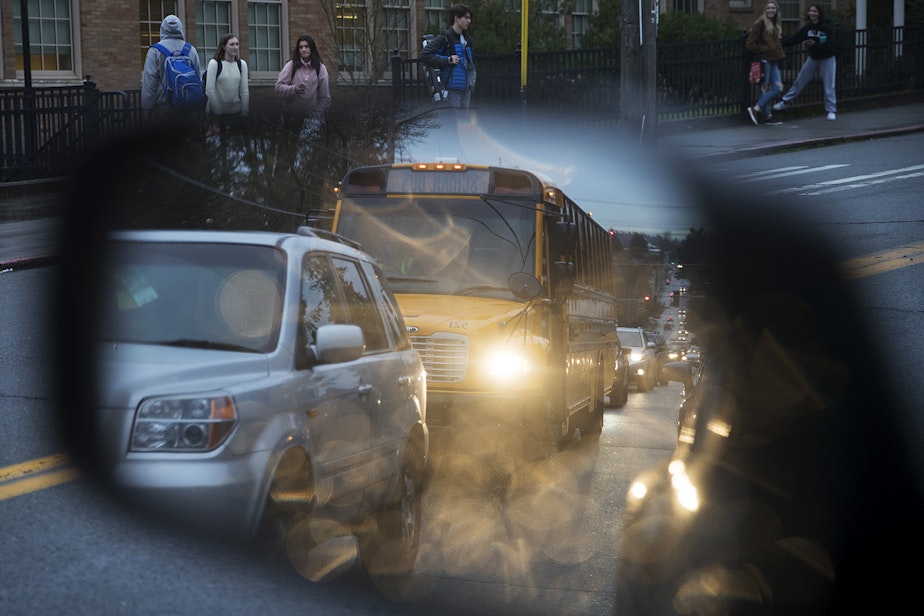 caption: A school bus is shown in vehicle's mirror as students pour out of Roosevelt High School on Tuesday, January 8, 2019, in Seattle. 