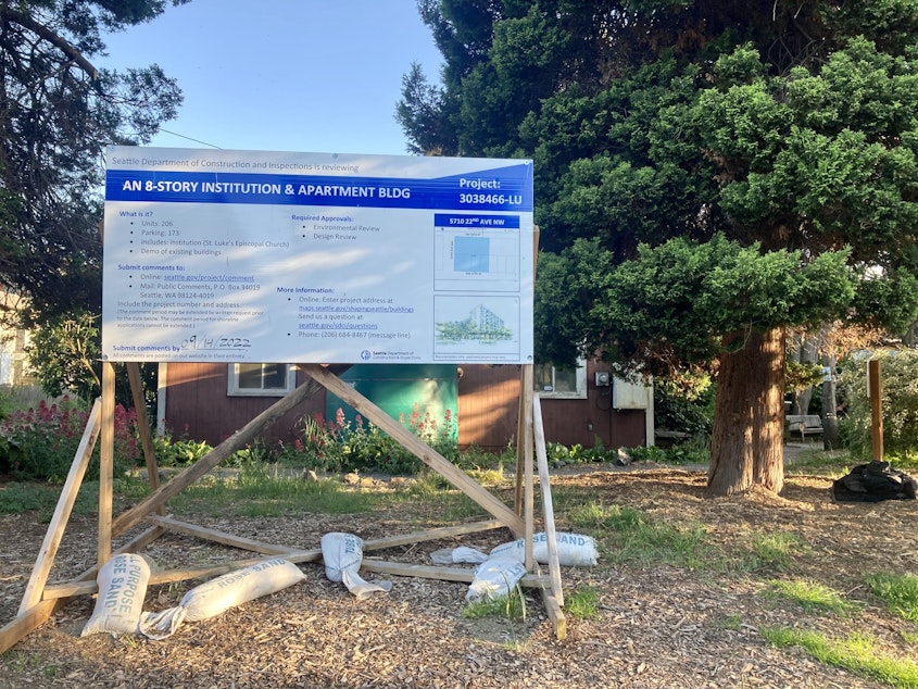 caption: A sign in front of the St Luke's Episcopal Church property in Ballard describes planned construction — an eight-story institution and apartment building.