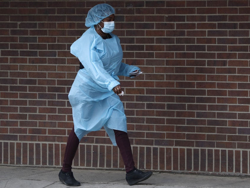 caption: A New York nurse wears personal protective equipment, which is in short supply. The Trump administration says it won't allow firms to export masks and gloves until it is satisfied U.S. needs are being met.