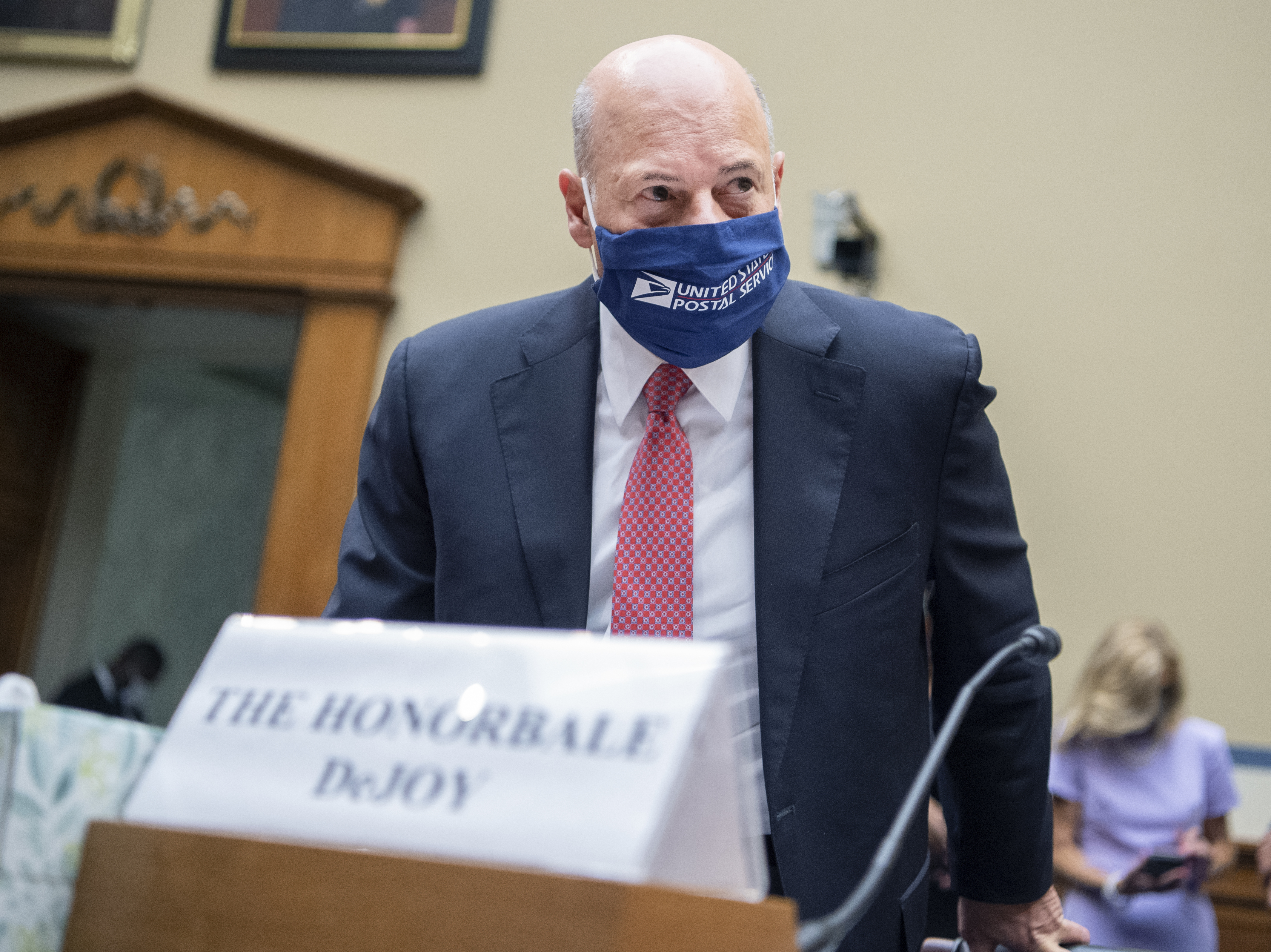caption: Postmaster General Louis DeJoy arrives to testify during a House Oversight and Reform Committee hearing in August.