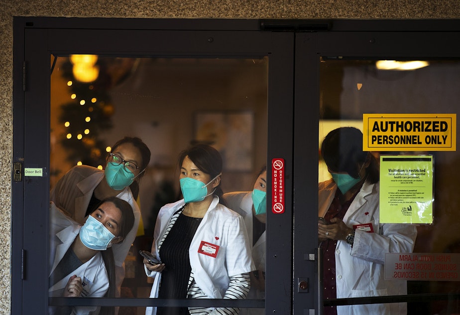 caption: Pharmacists with CVS look out of the front entrance of the Life Care Center of Kirkland ahead of the administration of the first Pfizer-BioNTech Covid-19 vaccinations for staff members on Monday, December 28, 2020, in Kirkland. 