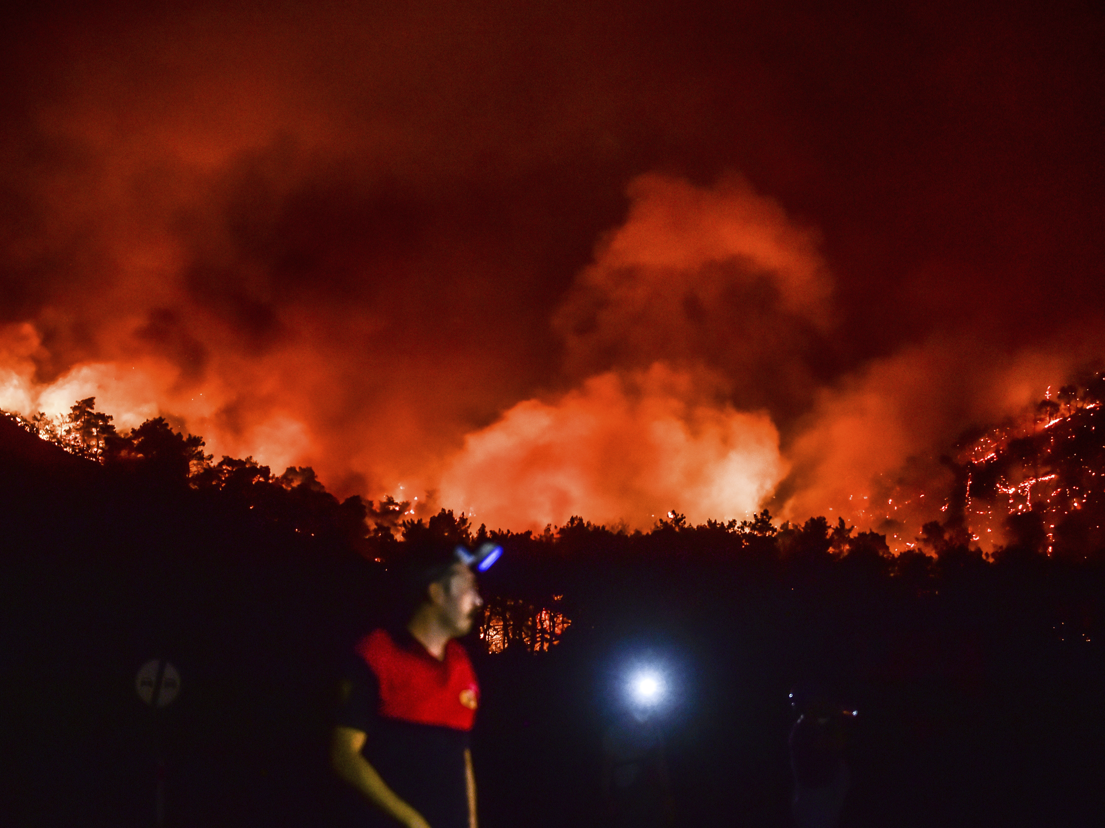caption: A man leaves as advancing fires rage the Hisaronu area, Turkey on Monday. For the sixth straight day, Turkish firefighters battled the blazes that are tearing through forests near Turkey's beach destinations.
