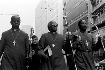 caption: South African activist and Anglican Archbishop Desmond Tutu (center) leads some 30 clergymen through Johannesburg to police headquarters in 1985 to hand in a petition calling for the release of political detainees.
