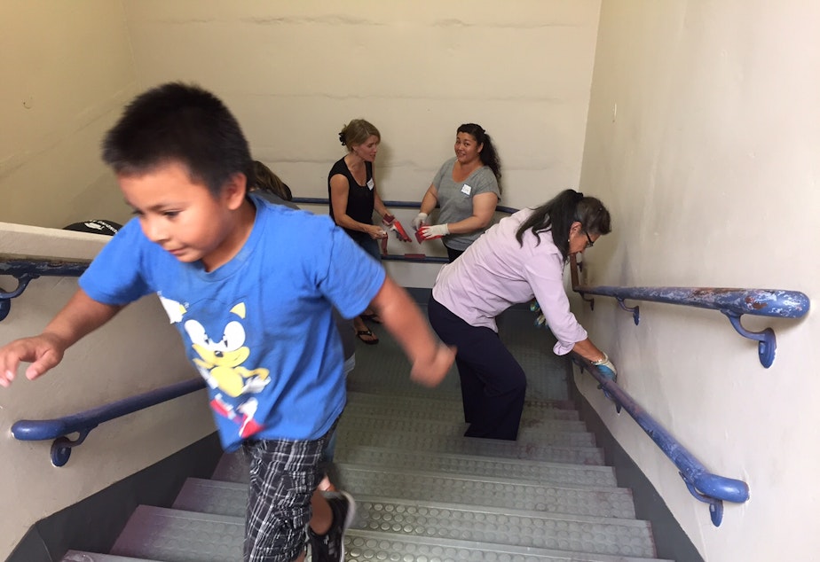caption: Families and staff at Rainier Prep sand old paint off railings in the school's adopted building at a recent work party.