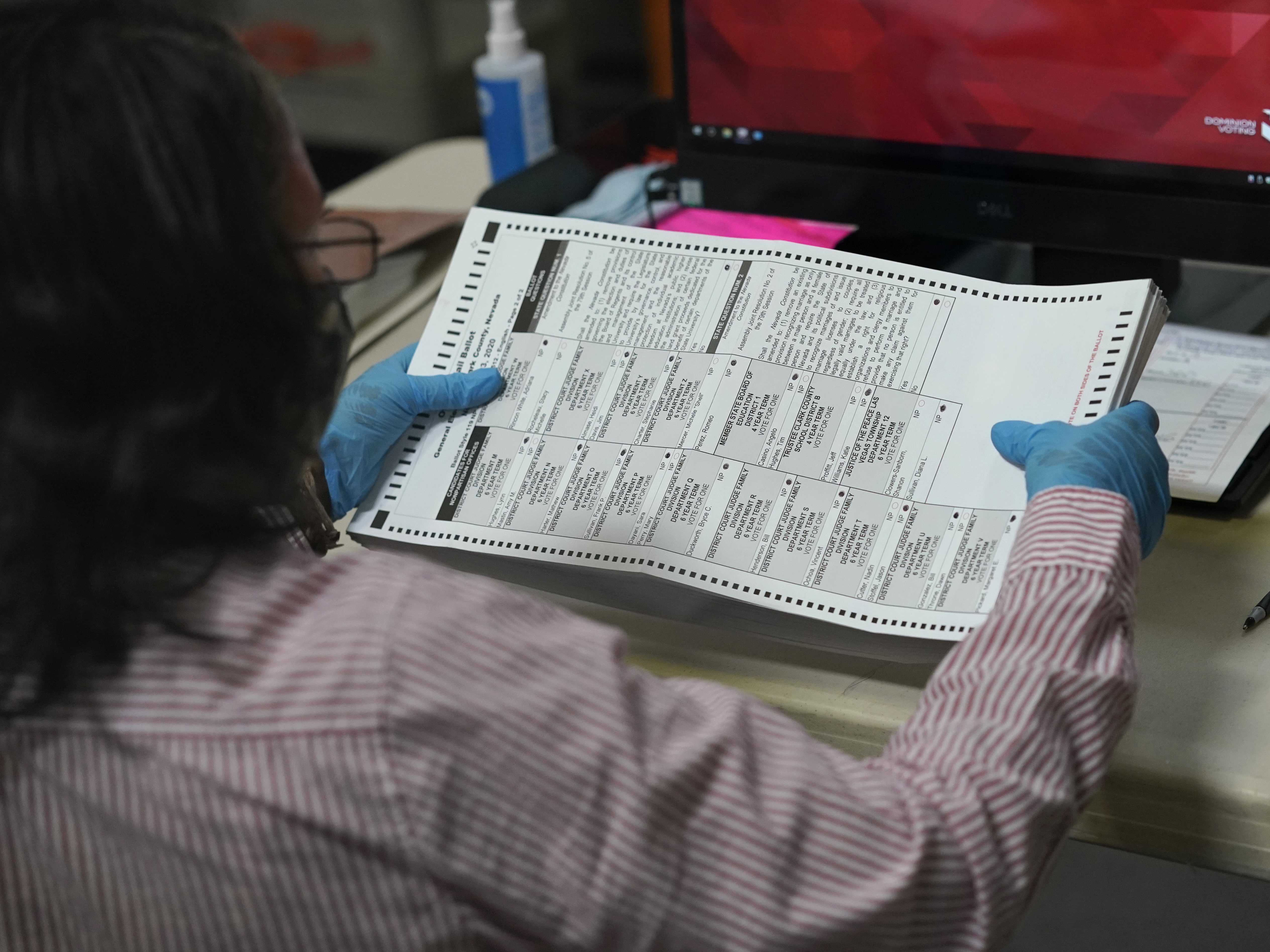 caption: A county worker loads mail-in ballots into a scanner that records the votes at the Clark County Election Department last Thursday in Las Vegas.