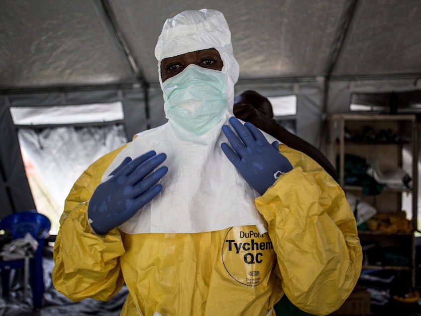 caption: A medical worker puts on protective gear at an Ebola treatment center in Beni in the Democratic Republic of the Congo. Officials want to train workers at all health facilities to take precautions.