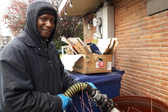 caption: Yurie Crockett sucks up used fry oil for recycling into biodiesel. His employer will pick up congestion tolling on his work vehicle (and he commutes by bus), but believes it will hurt people struggling to stay in the city.
