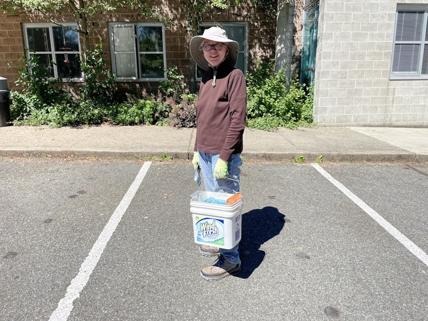 caption: Elizabeth Bixler picks up litter in the Meadowbrook Community Center parking lot in Seattle.