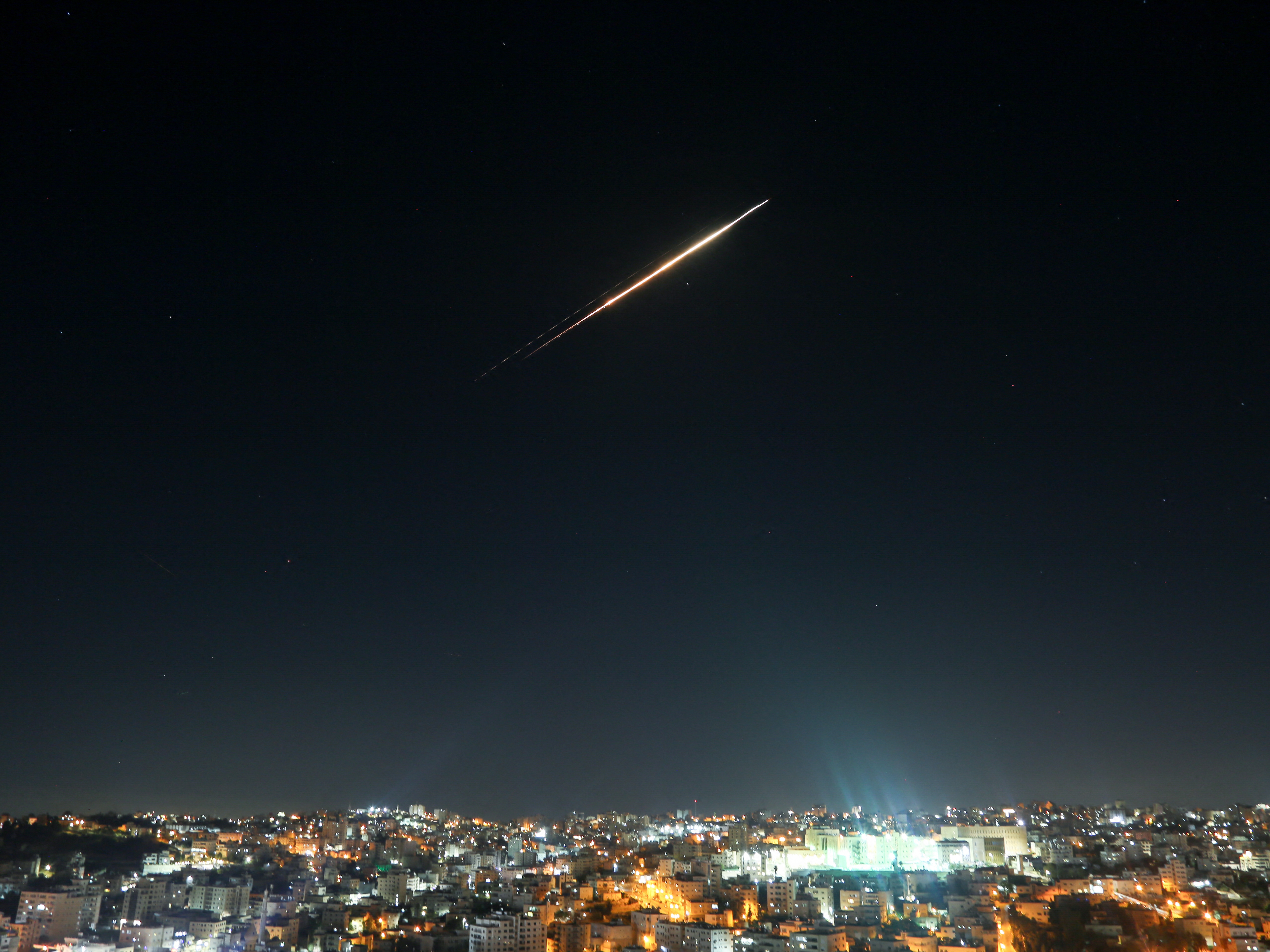 caption: Iranian missiles aimed at targets in Israel pass through the sky of Hebron, West Bank on June 18 as Israeli air defense system tries to intercept them.