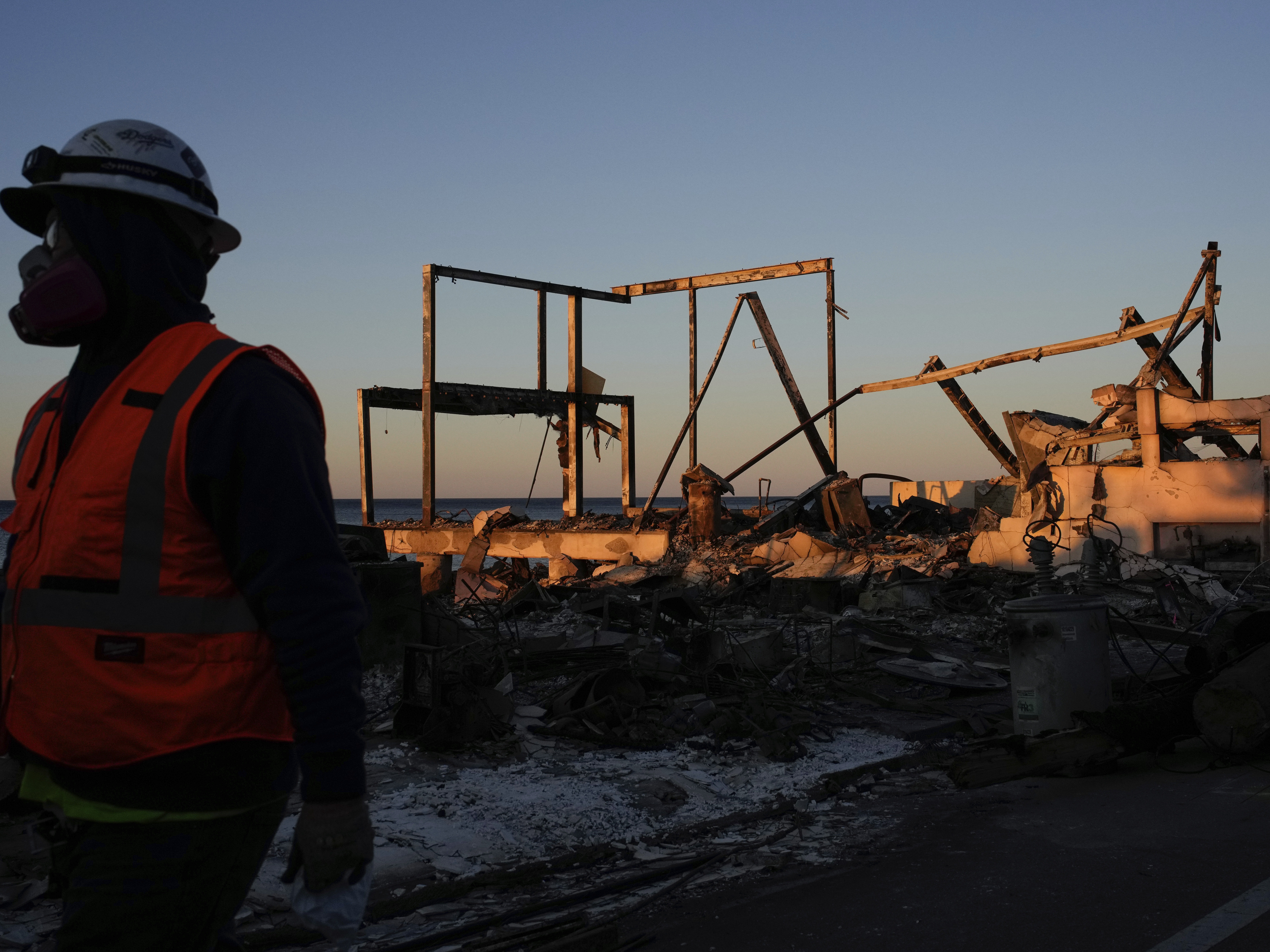 caption: A worker walks past a Palisades Fire-ravaged beachfront property in Malibu on Monday.