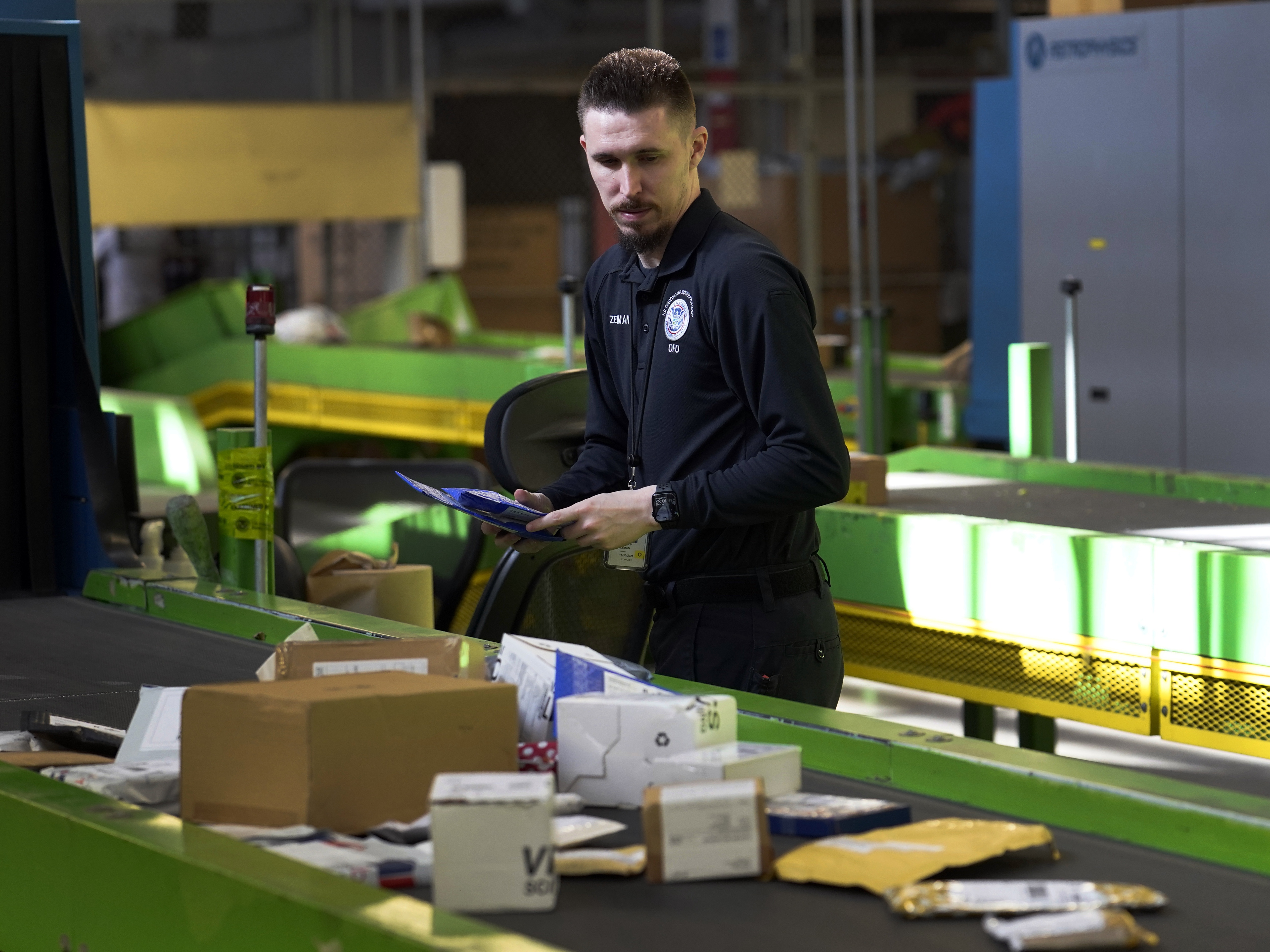 caption: A U.S. Customs and Border Protection technician examines overseas parcels after they were scanned at the agency's overseas mail inspection facility at Chicago's O'Hare International Airport on Feb. 23, 2024.