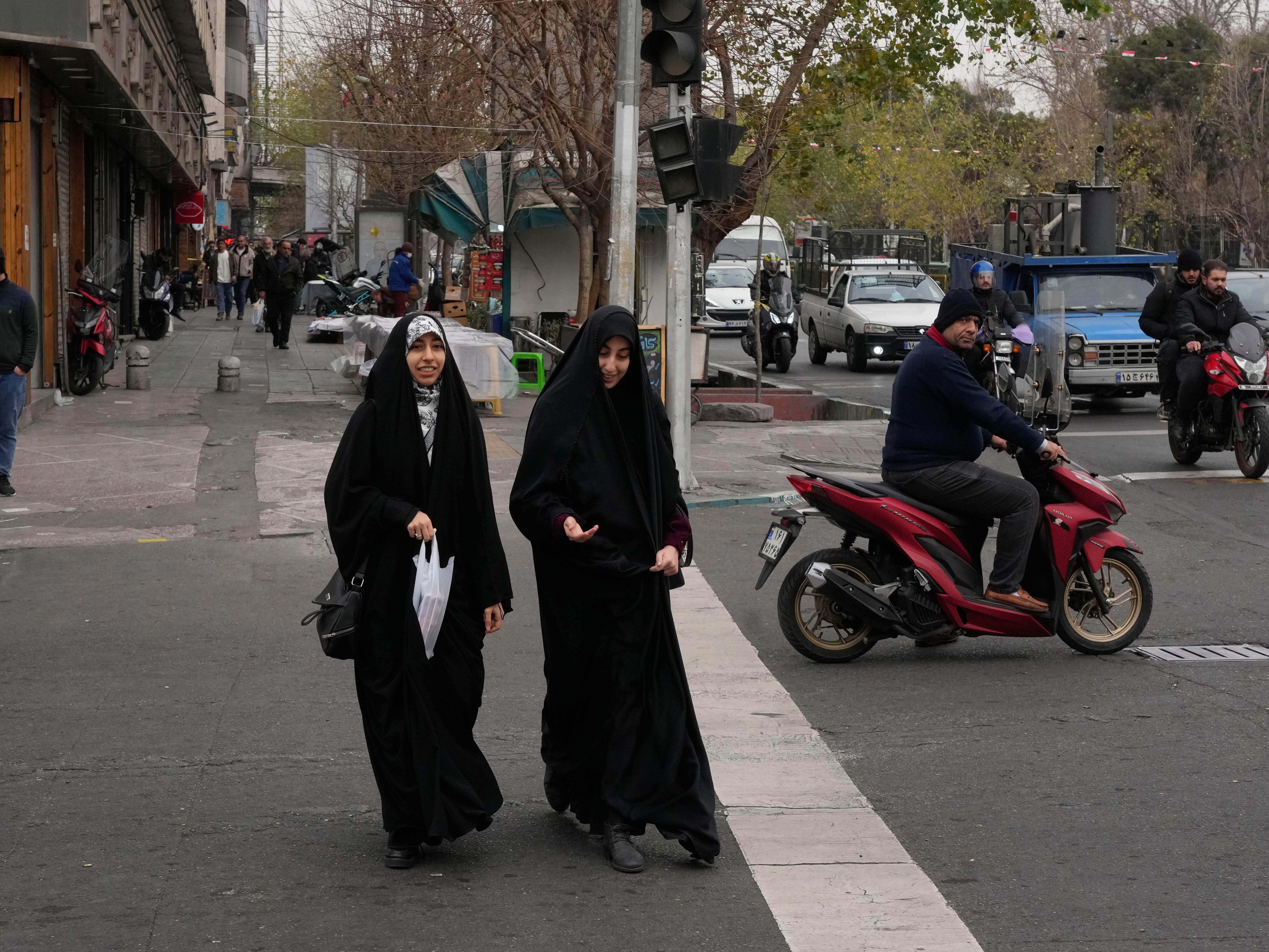 caption: Women cross an intersection in downtown Tehran, Iran, Thursday.