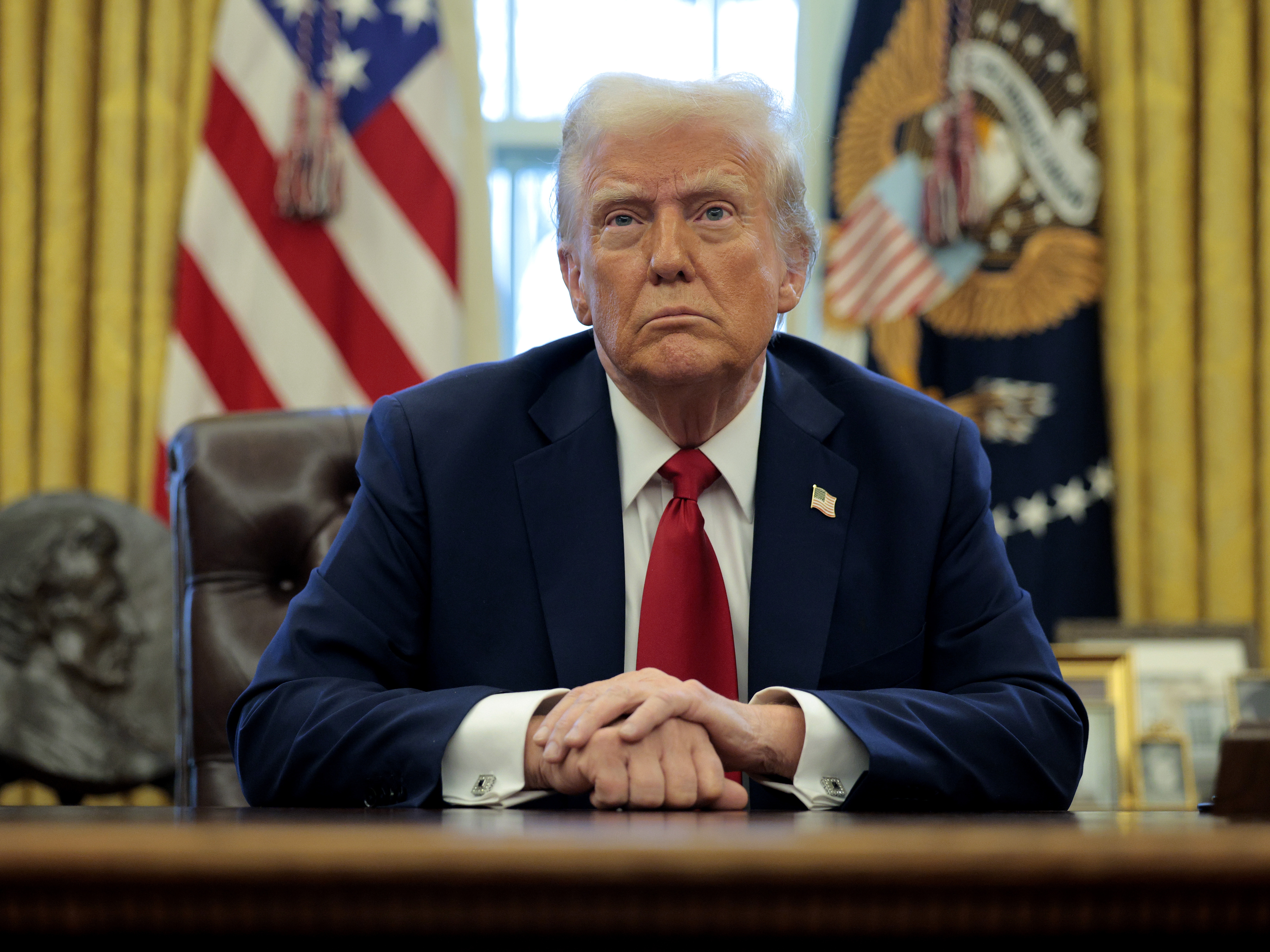 caption: President Trump talks to reporters from the Resolute Desk on Jan. 30.