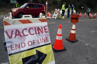 caption: Drivers with an appointment enter a COVID-19 vaccination site set up in the parking lot of Dodger Stadium in Los Angeles on Saturday. One of the largest vaccination sites in the country, it was temporarily shut down Saturday afternoon because of protesters, stalling hundreds of motorists who had been waiting in line for hours.