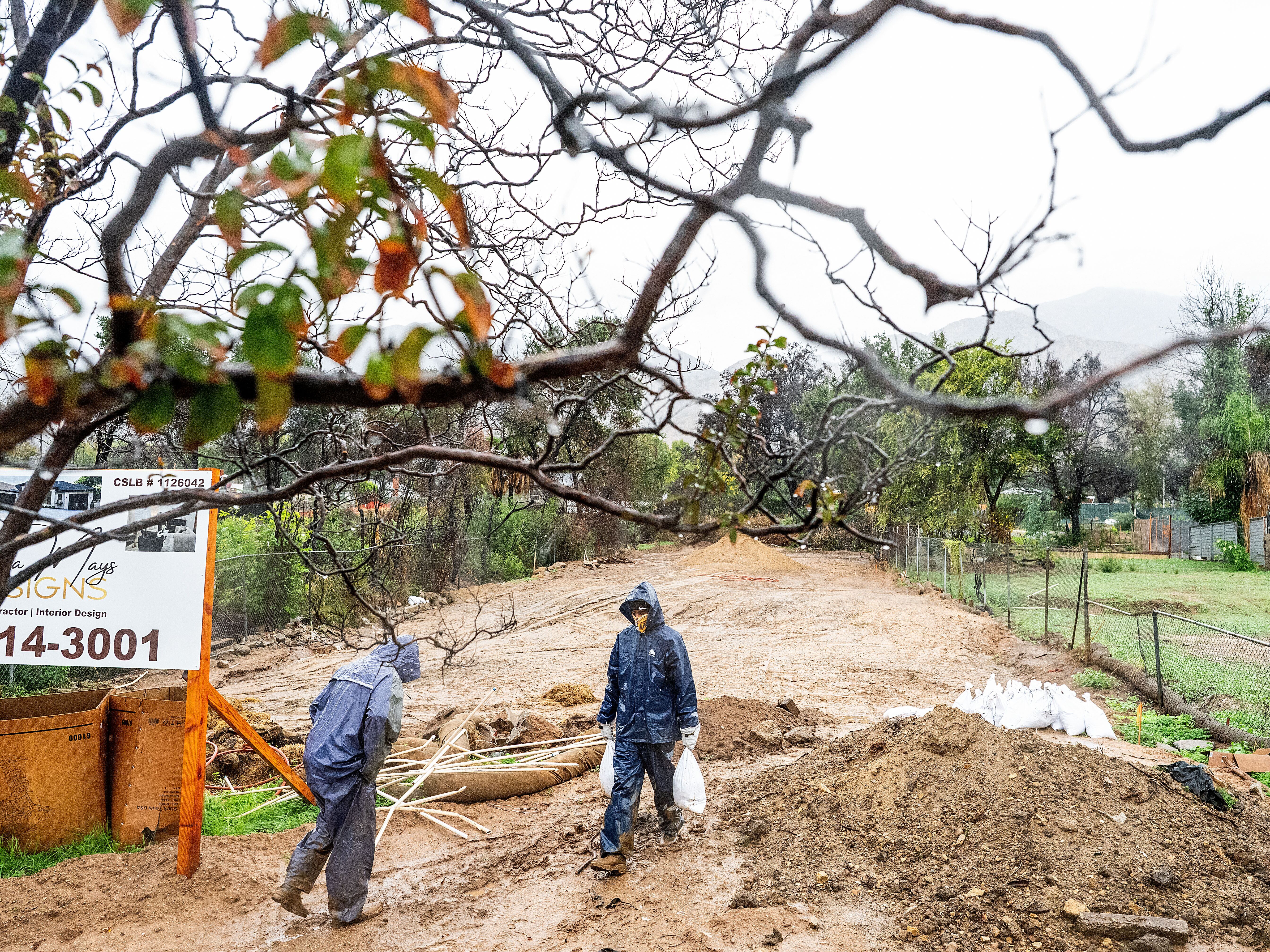 caption: James Jones carries sandbags while trying to prevent water from running off a property scorched in the Eaton Fire in Altadena, Calif., as the region remains under flash flood warnings on Saturday.
