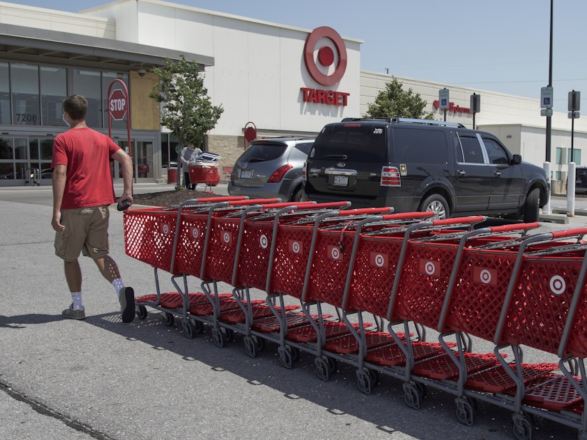 caption: A Target worker corrals shopping carts in Omaha, Neb., on June 16. The company is making permanent a $2 bonus it created during the pandemic, as many retailers have been phasing out "hazard pay."