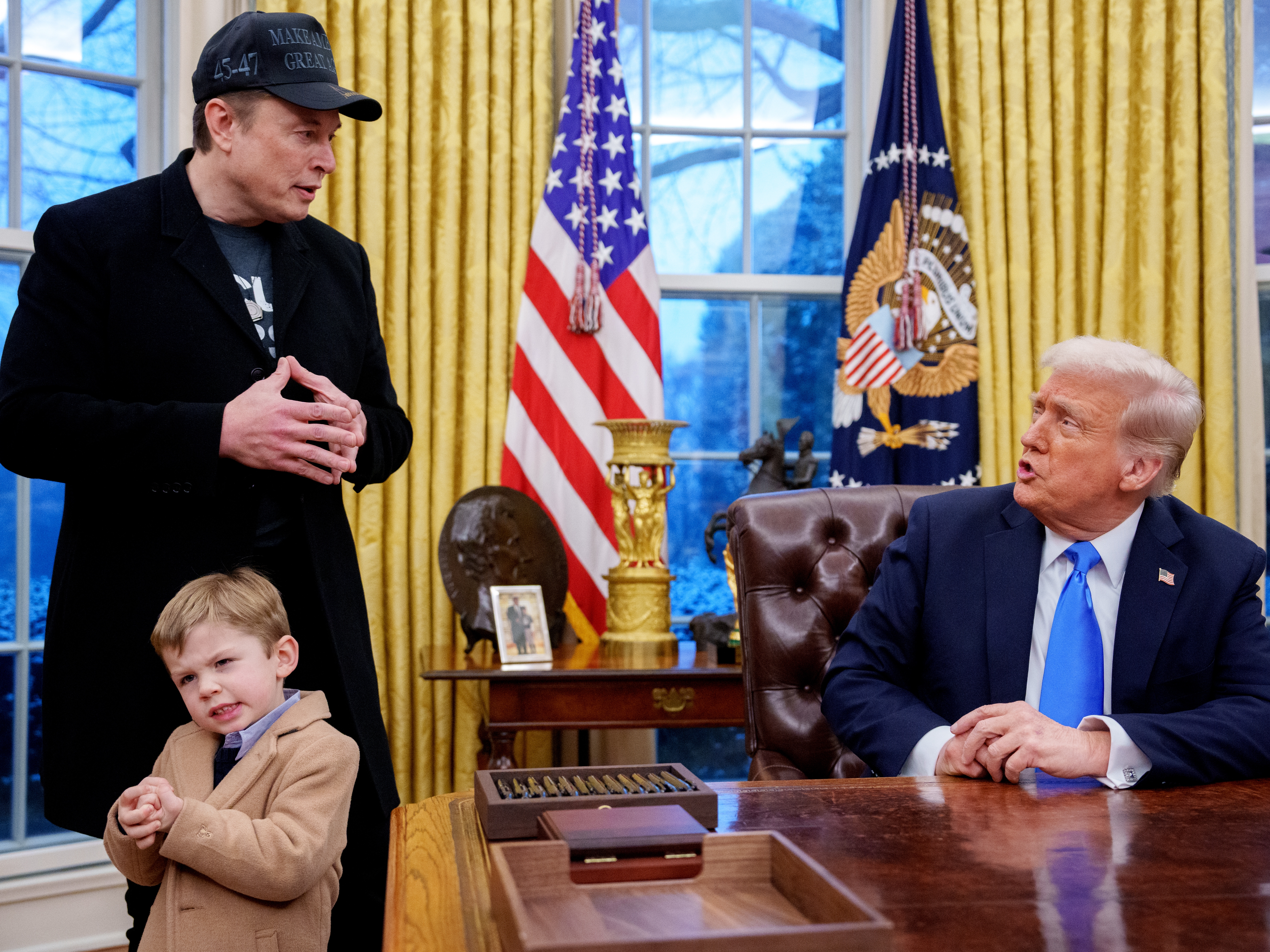 caption: President Trump is joined by Tesla and SpaceX CEO Elon Musk, and his son, X Musk, during an executive order signing in the Oval Office at the White House on Tuesday.