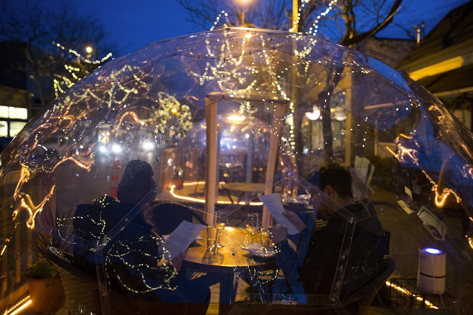 caption: Customers look at menus while dining inside of a clear dome structure outside of San Fermo on Sunday, November 15, 2020, along Ballard Avenue Northwest in Seattle. New statewide restrictions, including a ban on indoor dining beginning Wednesday, were announced by Gov. Jay Inslee on Sunday to curb the rapid spread of Covid-19. 