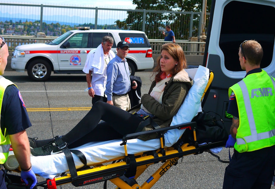 caption: A woman is taken to an ambulance on the Aurora Bridge after the crash Thursday.