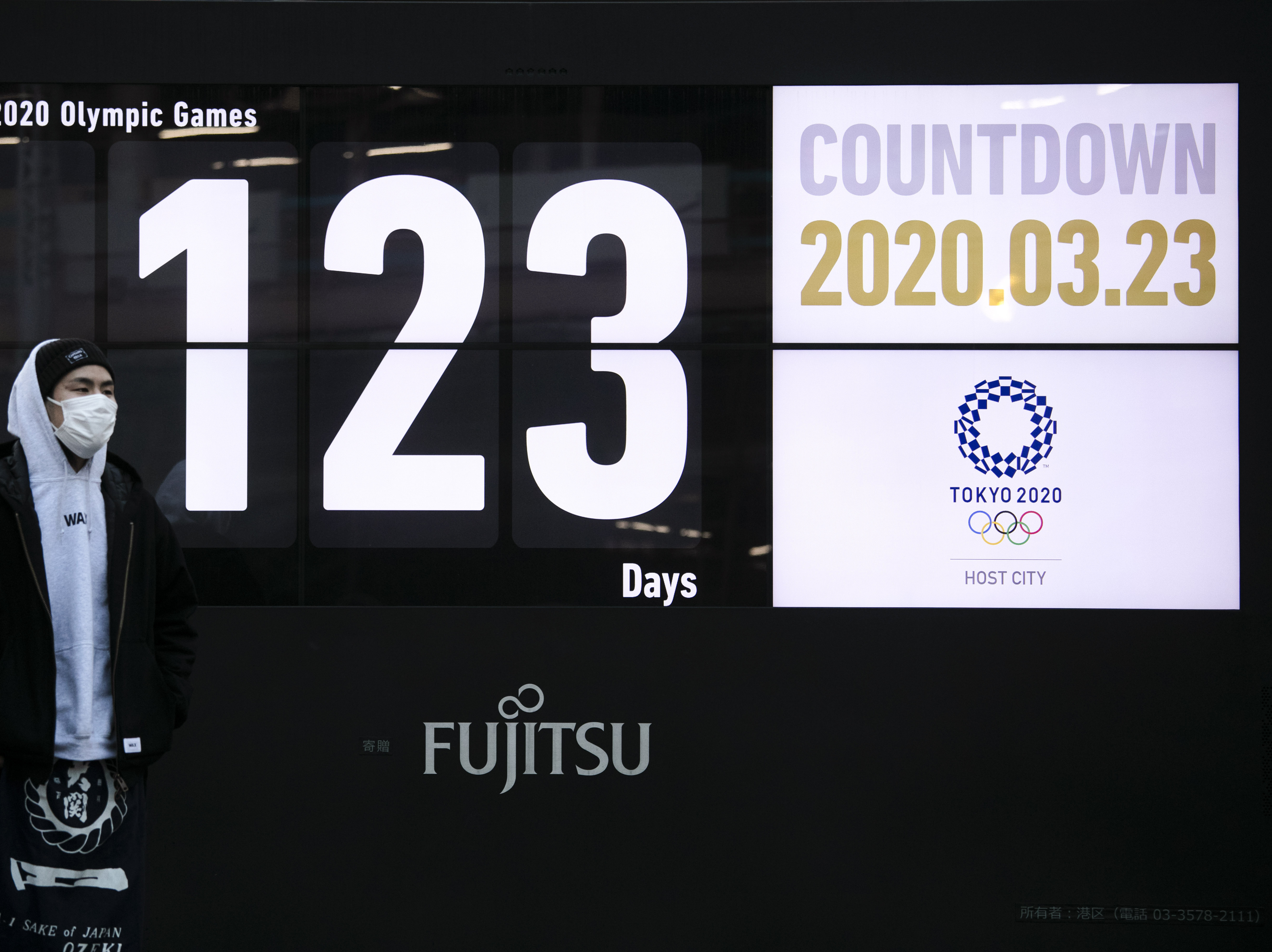 caption: A man stands in front of a countdown display for the Tokyo 2020 Olympics and Paralympics in Tokyo, on Monday. Japan's Prime Minister Shinzo Abe acknowledged that a postponement of the crown jewel of the sporting world could be unavoidable.