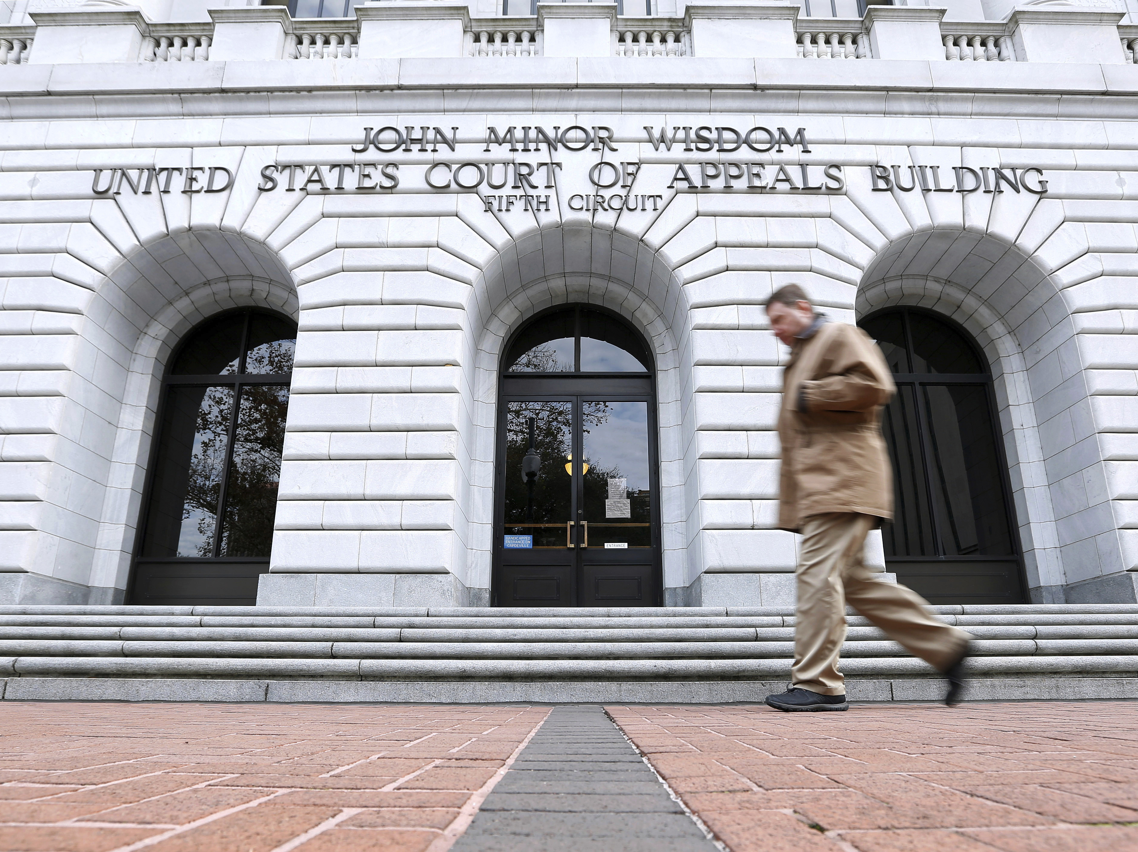 caption: A man walks in front of the 5th U.S. Circuit Court of Appeals on Jan. 7, 2015, in New Orleans.