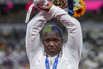 caption: Team USA's Raven Saunders with her silver medal in the women's shot put event Sunday at the Tokyo Olympics. During the medal ceremony, Saunders lifted her arms above her head and formed an "X' with her wrists.
