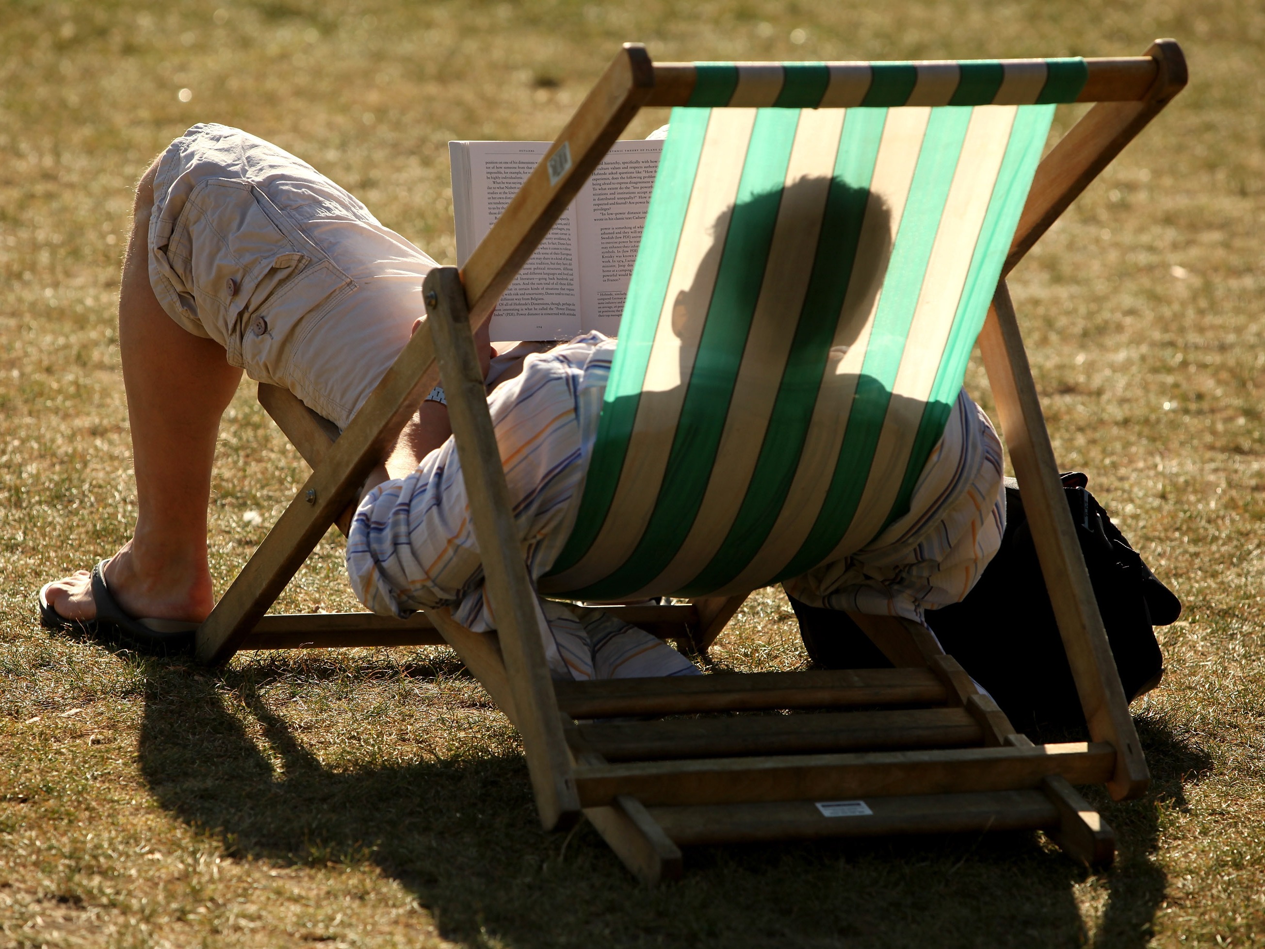 caption: A syndicated, AI-generated summer reading list featuring fake books by real authors was published in major newspapers this week. Above, a reader enjoys the sunshine in Hyde Park in London in 2009.