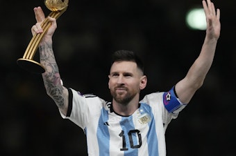 caption: Argentina's Lionel Messi waves after receiving the Golden Ball award for best player at the end of the World Cup final soccer match between Argentina and France at the Lusail Stadium in Qatar on  Dec. 18, 2022.