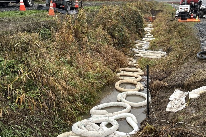 caption: Spill-containment boom floats in a ditch on a blueberry farm near Everett, Washington, on Nov. 18, 2025, after a spill of jet fuel from the Olympic Pipeline.