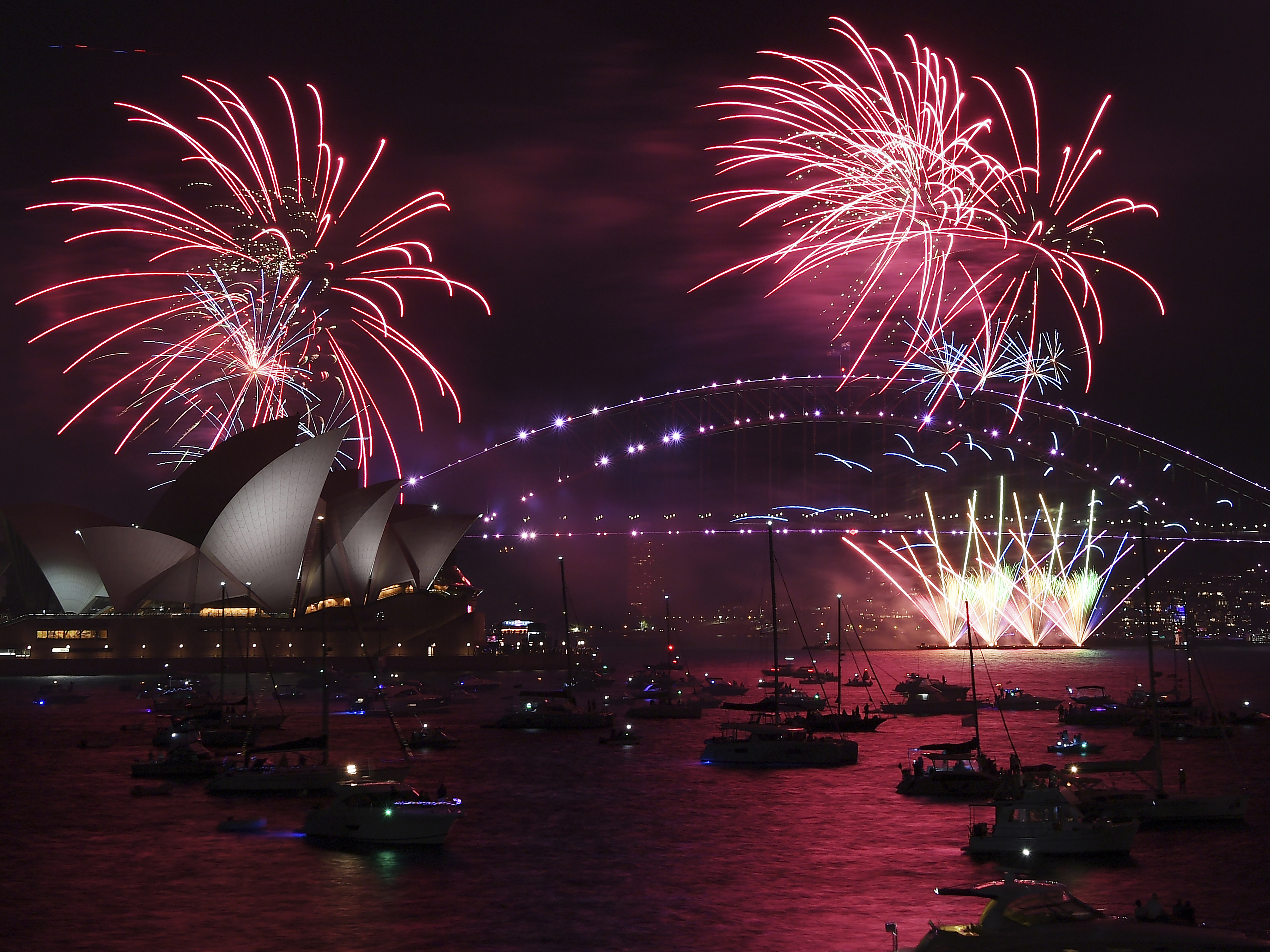 caption: Fireworks explode over the Sydney Opera House and Harbour Bridge as New Year's Eve celebrations begin in Sydney, on Friday.