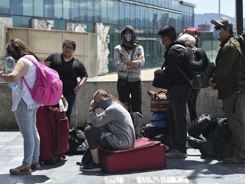 caption: Travelers wait for a charter flight coordinated by the United States embassy to take them home from Guatemala City on Monday.
