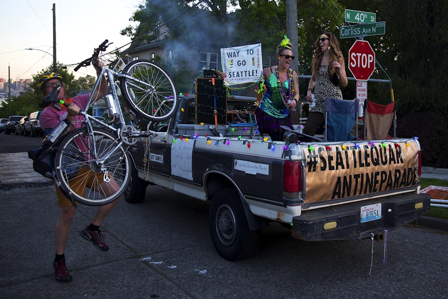 caption: A cyclist dances alongside members of the Seattle Quarantine Parade, Lindsey Hornickel and Darcy Newby, right, on Friday, May 8, 2020, at the intersection of Corliss Avenue North and North 40th Street in Seattle.