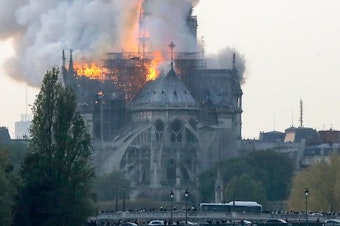 caption: Smoke ascends as flames rise during a fire at the landmark Notre Dame Cathedral in central Paris on April 15, 2019.
