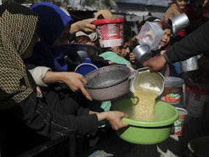caption: Palestinians line up for a meal in Rafah on Wednesday.