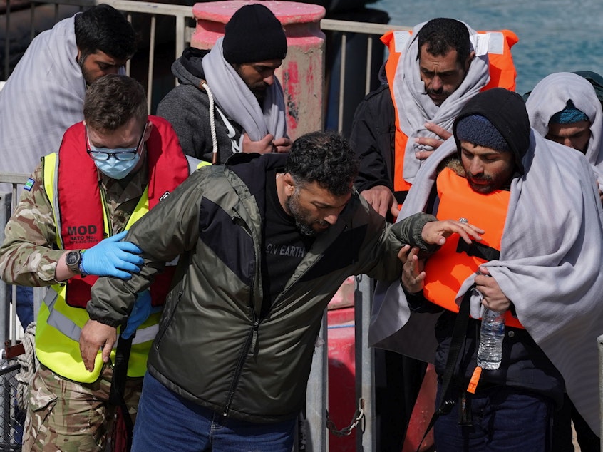 caption: A group of people thought to be migrants are brought in to Dover, Kent, by the RNLI, following a small boat incident in the Channel, Thursday April 14, 2022.