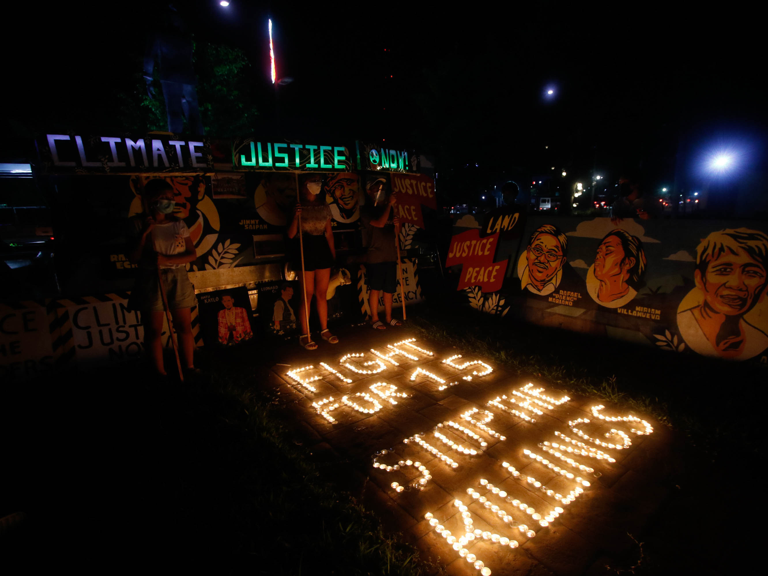 caption: Climate activists in Quezon City, Philippines, light candles and hold LED-illuminated banners in December of last year to commemorates five years since the Paris Agreement and to call for an end to the killing of environmental defenders.