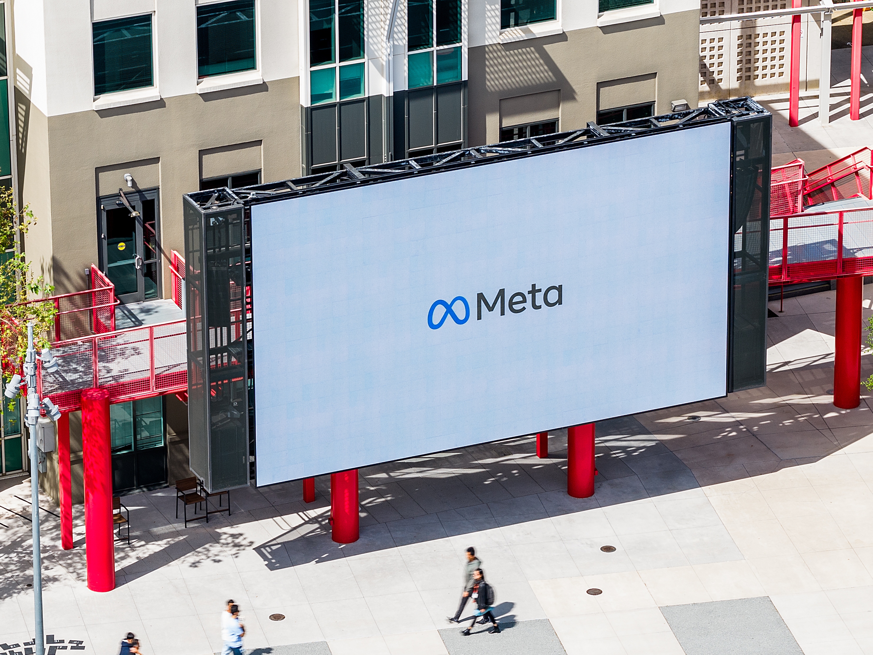 caption: Workers walk past a display at Meta headquarters on Thursday, March 26, 2026, in Menlo Park, Calif.