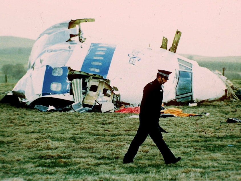 caption: A police officer walks by the nose of Pan Am Flight 103 in a field near the town of Lockerbie, Scotland in 1988.