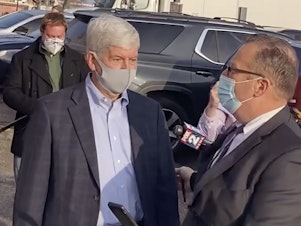 caption: In this image taken from video, former Michigan Gov. Rick Snyder, left, with his lawyer, Brian Lennon, leave Genesee County Court in Flint, Mich., after a initial court appearance via Zoom on two misdemeanor counts of willful neglect of duty in connection to the Flint water crisis.
