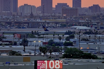 caption: A sign displays an an unofficial temperature as jets taxi at Sky Harbor International Airport at dusk, July 12 in Phoenix.