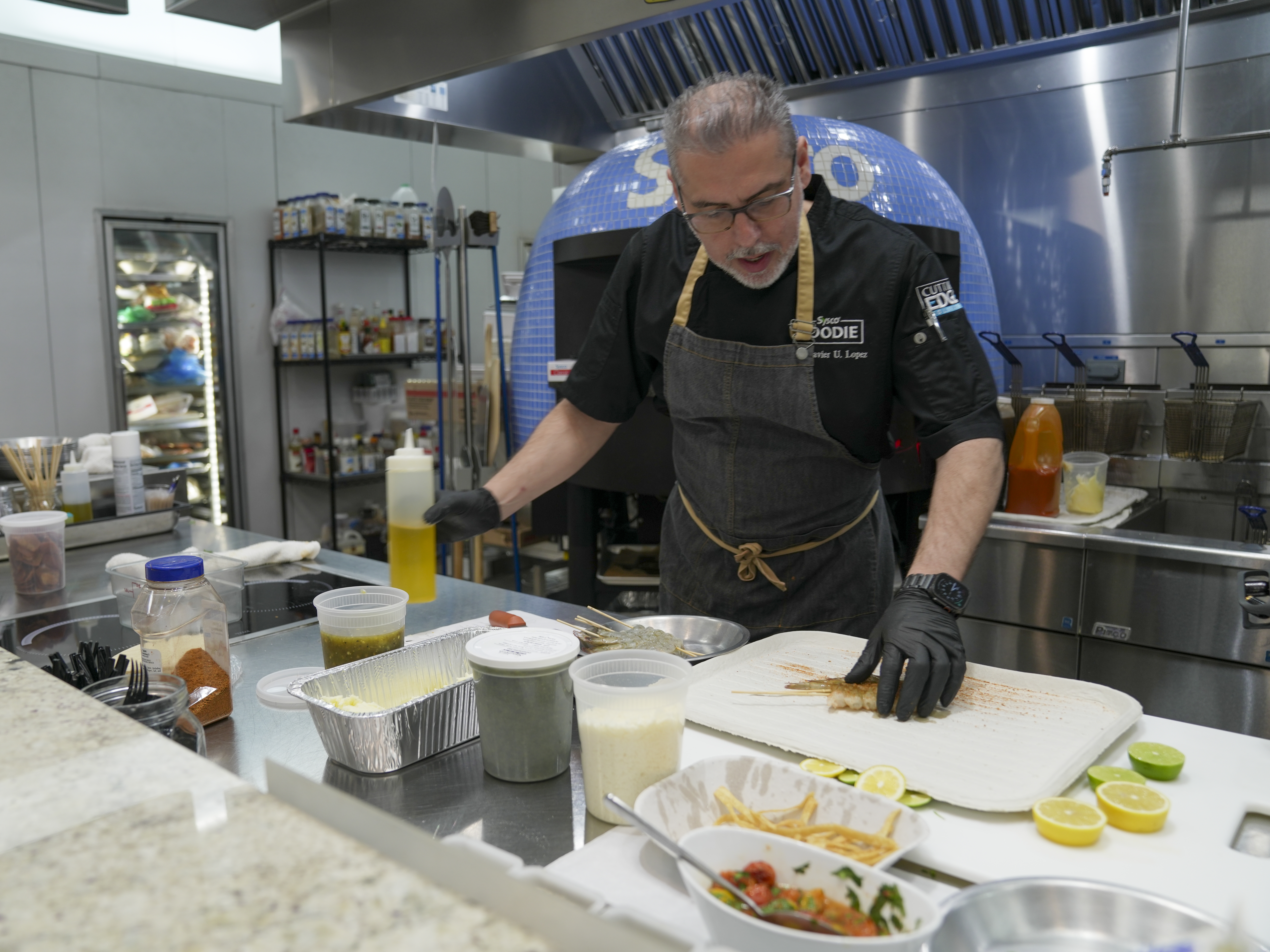 caption: Chef Javier U. Lopez prepares fresh food in the Sysco test kitchen, at their distribution center in Houston. Sysco Corporation helps restaurateurs get the best bang for their buck by providing everything from pre-cut ingredients to menu creation.