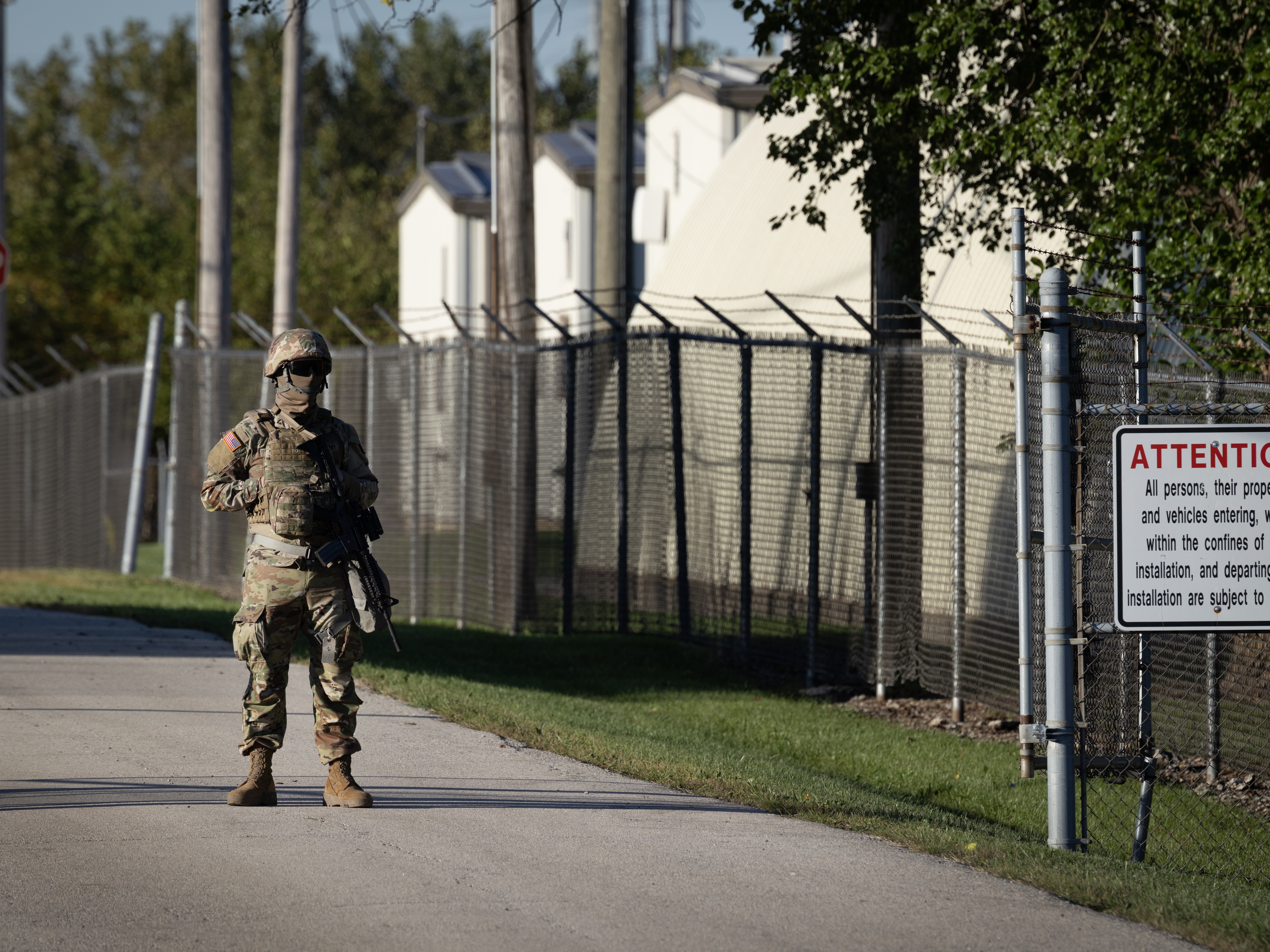 caption: A member of the Texas National Guard stands at an army reserve training facility on October 07, 2025 in Elwood, Illinois.