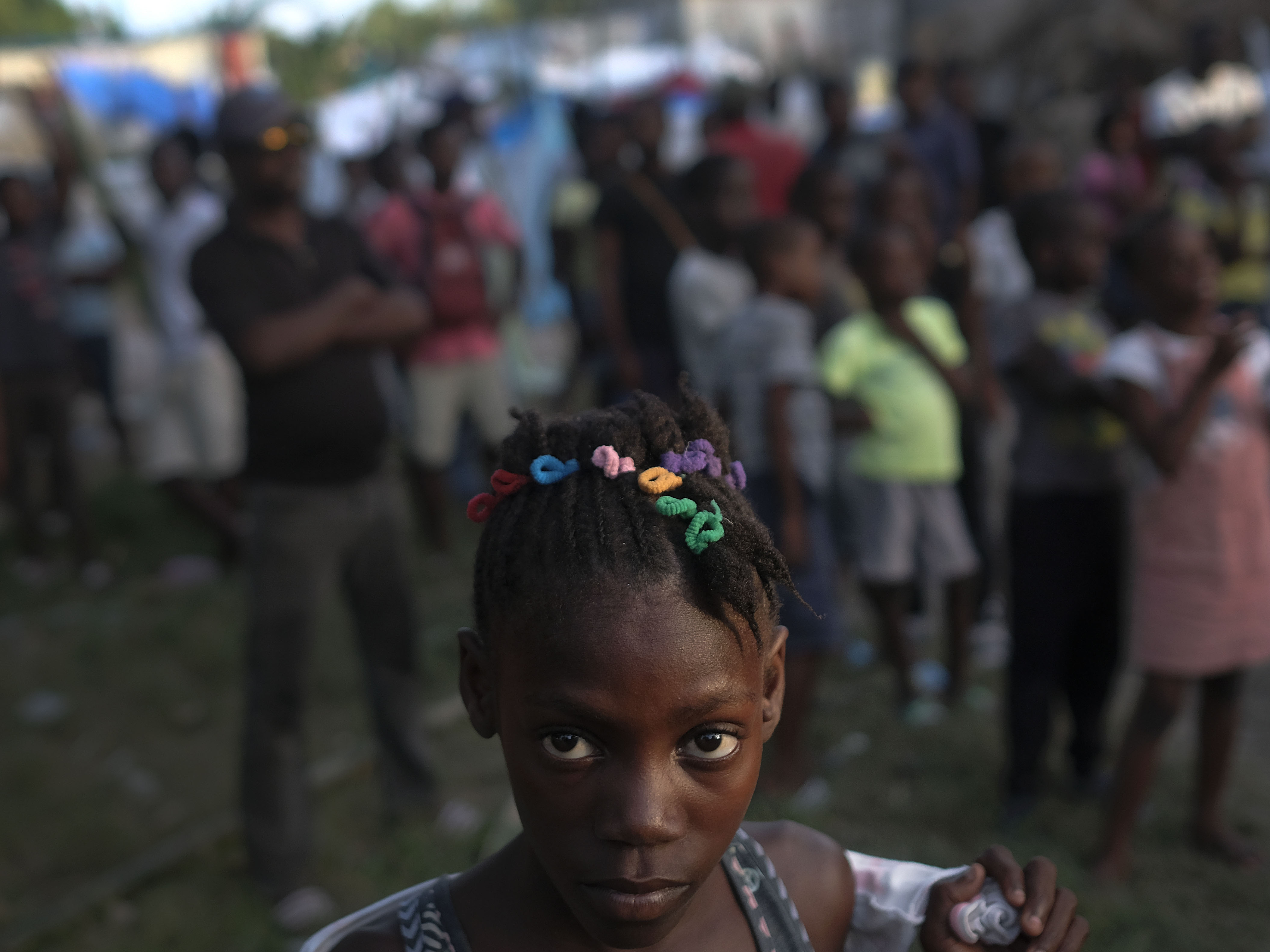 caption: A girl waits with other earthquake victims for the start of a food distribution in Les Cayes, Haiti, in August, a week after a 7.2 magnitude earthquake hit the area.