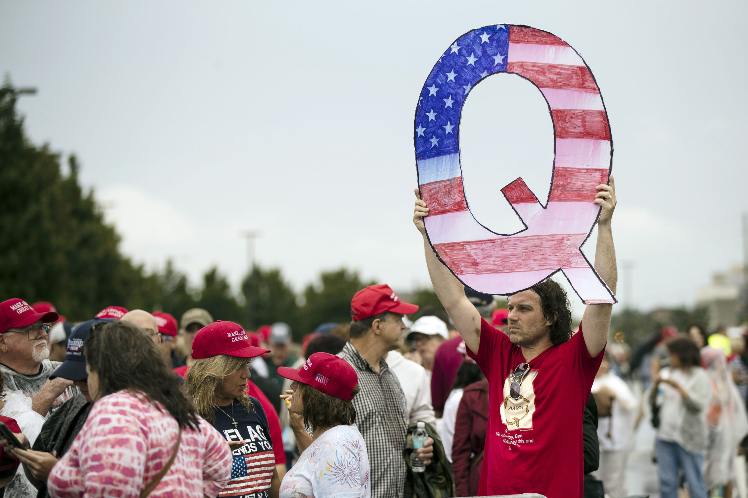 caption: In this Aug. 2, 2018 file photo, David Reinert holding a Q sign waits in line with others to enter a campaign rally with President Donald Trump in Wilkes-Barre, Pa. (Matt Rourke, File/AP)