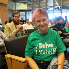 caption: Uber provided drivers like Suzy Harrison with shirts that say, 'I Drive, I Vote.'