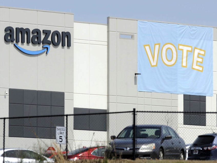 caption: A banner encourages workers to vote in a union election at Amazon's warehouse in Bessemer, Ala.