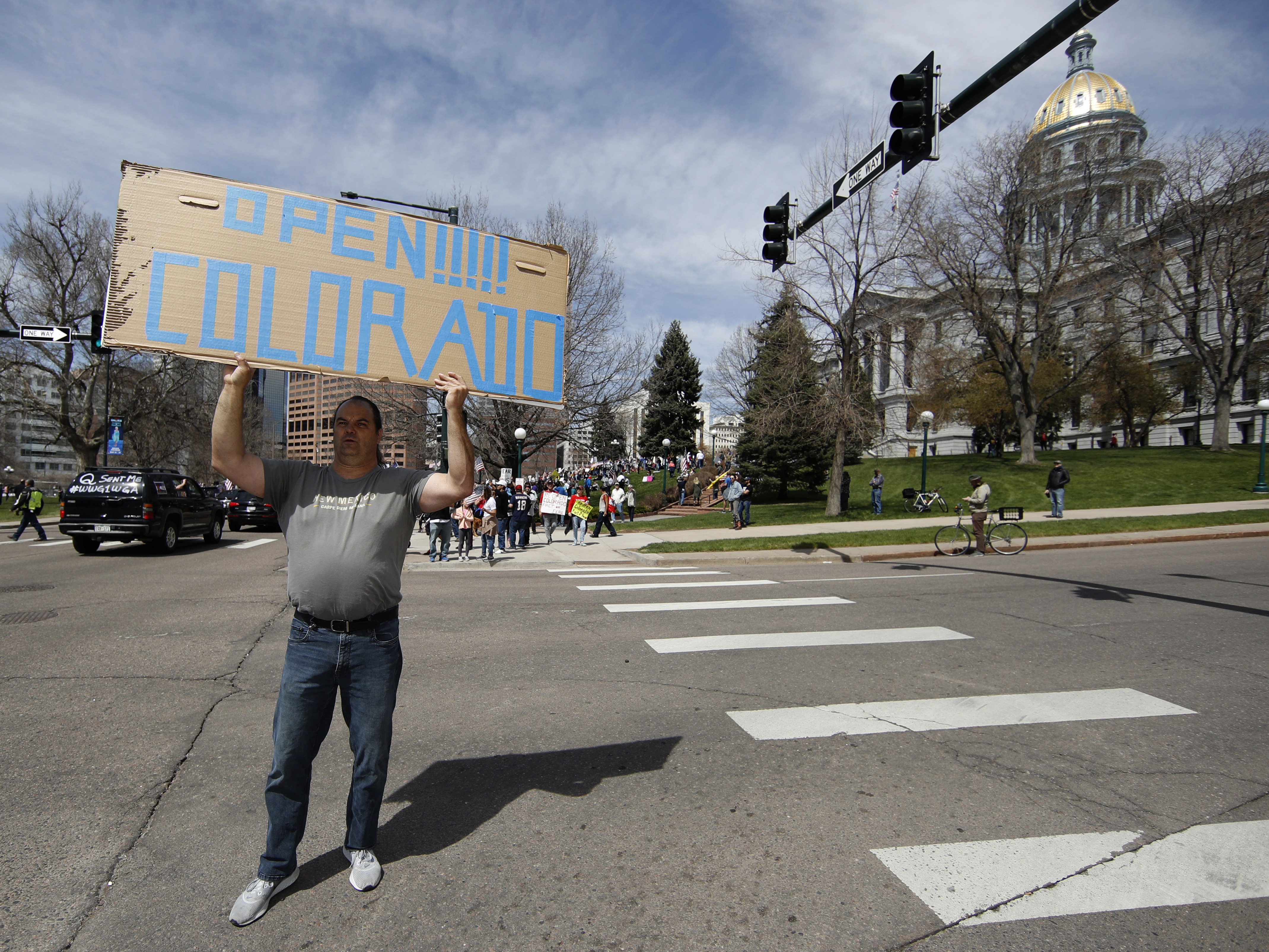caption: A protester waves a placard during a car protest against the stay-at-home order issued by Colorado Gov. Jared Polis to stem the spread of the new coronavirus on April 19 in Denver.