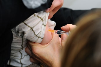 caption: A child is immunized against measles, mumps and rubella in Lyon, France.